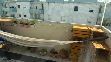 Gemütlicher Balkon mit Hängematte, Pflanzen und Holzkisten als Stauraum oder Dekoration.