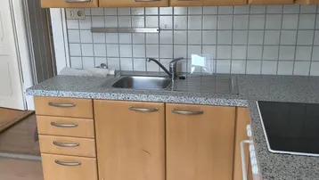 Helle Küche mit Holzschränken, Granitarbeitsplatte und Fliesenrückwand, bereit für den täglichen Gebrauch.