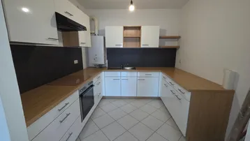 Helle Küche mit weißen Schränken, Holz-Arbeitsplatten und Fliesenboden, ausgestattet mit einem Ofen.