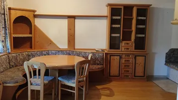 Gemütlicher Wohn-Essbereich im alpinen Stil mit Eckbank, Holztisch und Schrankwand.