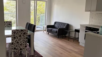 Heller offener Wohn- und Essbereich mit integrierter Küche, Parkettboden und Zugang zum Balkon.