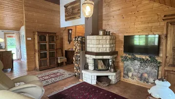 Rustikales Wohnzimmer mit Kamin, Holzwänden, Fliesenboden und bequemen Sesseln.