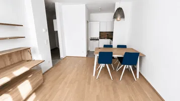 Heller offener Wohn- und Essbereich mit moderner Küche und Holzfußboden.