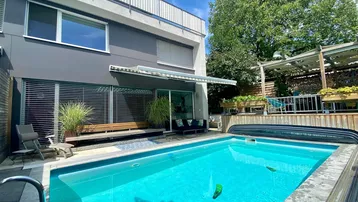 Modernes Haus mit privatem Pool und Terrasse im Gartenbereich unter blauem Himmel.