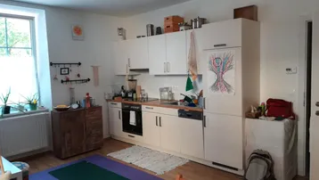 Helle Küche mit weißen Schränken, Holzboden und einem Fenster, das viel Tageslicht hereinlässt.