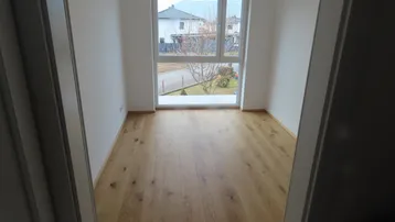 Helles Zimmer mit großem Fenster und Holzboden, ideal als Schlaf- oder Arbeitszimmer.