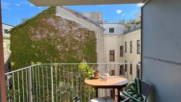 Gemütlicher Balkon mit Sitzgelegenheiten und Blick auf einen begrünten Innenhof.