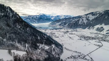 Atemberaubende Winterlandschaft mit schneebedeckten Bergen, einem See und einem malerischen Dorf im Tal.