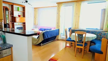 Heller offener Wohn- und Essbereich mit Holzboden und Zugang zum Balkon.