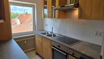 Kleine Küche mit Holzschränken, integrierten Geräten und Blick auf die Dächer.