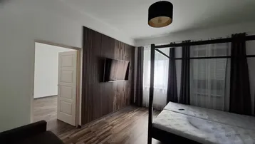 Geräumiges Schlafzimmer mit Holzwandverkleidung, Doppelbett und Blick nach draußen.