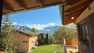 Geräumiger Holzbalkon mit traditionellem Dachüberstand und weitem Blick auf die umliegende Berglandschaft.