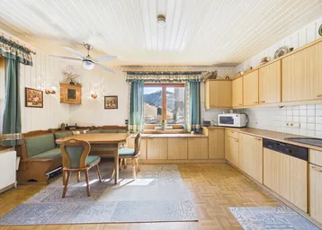 Gemütliche Wohnküche im Landhausstil mit Holzeinbauten, Essbereich und weitem Bergblick.