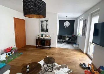 Heller offener Wohnbereich mit Holzboden, moderner Einrichtung und Blick auf den Essbereich.