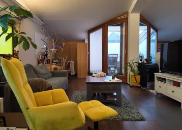 Helles Wohnzimmer mit gemütlicher Einrichtung, Holzboden und Zugang zu einer Dachterrasse.
