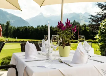 Einladender Esstisch auf der Terrasse mit atemberaubendem Bergblick und grüner Umgebung.