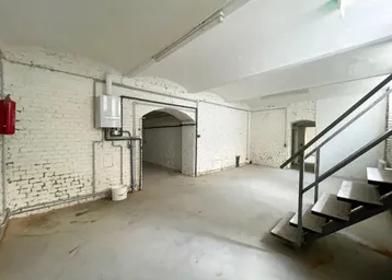 Geräumiger Kellerraum mit weiß gestrichenen Ziegelwänden, Betonboden und sichtbarer Heizungsanlage.