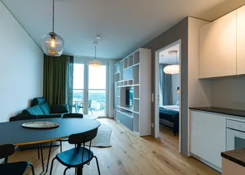 Moderner offener Wohnbereich mit Holzboden, Essbereich und integrierter Küche, mit Zugang zum Balkon.