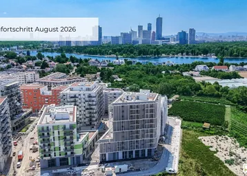Luftaufnahme eines Neubaukomplexes im Bau mit Fluss und Stadtpanorama im Hintergrund.