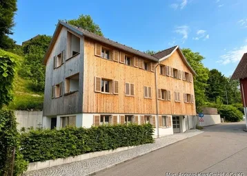 Modernes Mehrfamilienhaus mit Holzfassade und traditionellen Fensterläden, eingebettet in eine grüne Hanglage.
