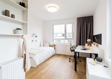 Helles Schlafzimmer mit Einzelbett, Schreibtisch, Regal und großem Fenster.