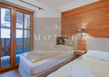Gemütliches Schlafzimmer im alpinen Stil mit zwei Einzelbetten und Zugang zum Balkon mit Bergblick.