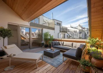 Geräumige Dachterrasse mit bequemen Loungemöbeln, Sonnenliege und Holzboden für entspannte Stunden im Freien.