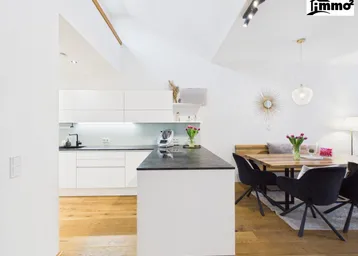 Moderne offene Küche mit Kücheninsel, Essbereich und Holzboden in einem hellen Raum.