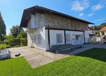 Außenansicht eines Hauses im Rohbauzustand mit Rasenfläche im Vordergrund.