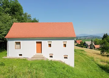 Kleines Gebäude mit rotem Ziegeldach und Blick auf die umliegende Landschaft und Siedlung.