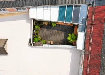 Dachterrasse mit Holzboden, Pflanzen und Glasüberdachung, von oben betrachtet, bietet einen privaten Außenbereich.