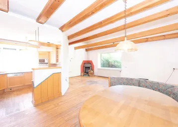 Offener Wohn-Essbereich mit Kamin, Holzbalken und rustikalem Holzboden.