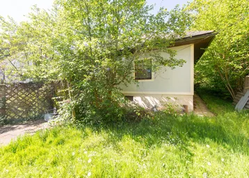 Einfaches Haus mit bewachsenem Garten und viel Grün in ländlicher Umgebung.