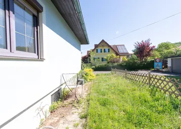 Seitenansicht eines Hauses mit Rasenfläche und Blick auf die Nachbarschaft.