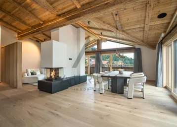 Geräumiger Wohn-Essbereich mit Holzbalkendecke, modernem Kamin und hellem Parkettboden.