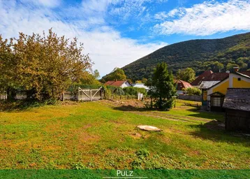 Großer Gartenbereich mit Rasenfläche, Bäumen und Blick auf die umliegende Landschaft und Hügel.
