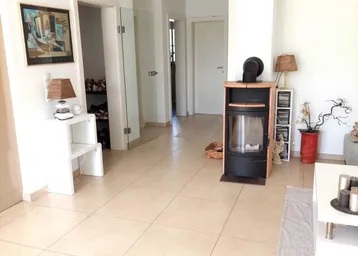 Heller Eingangsbereich und Wohnzimmer mit Fliesenboden und modernem Holzofen als Blickfang.
