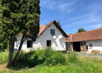 Blick auf das ländliche Wohnhaus mit Satteldach und üppigem, grünem Gartenbereich.