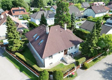 Luftaufnahme eines Einfamilienhauses mit braunem Ziegeldach und gepflegtem Gartenbereich.