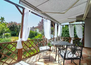 Geräumige überdachte Terrasse mit schmiedeeisernen Möbeln und Blick ins Grüne, ideal zum Entspannen.