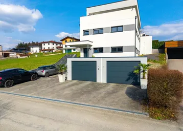 Modernes Wohnhaus mit Doppelgarage, Auffahrt und gepflegter Außenanlage in ländlicher Umgebung.