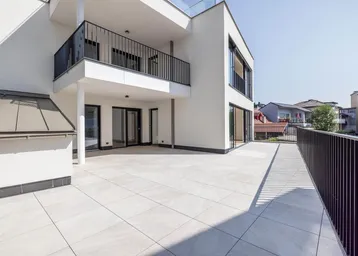 Große, helle Terrasse mit modernen Fliesen und schwarzem Geländer, ideal für Entspannung im Freien.