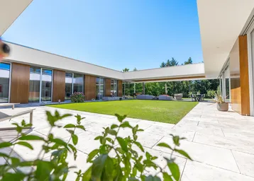 Moderner Innenhof mit gepflegtem Rasen, großzügiger Terrasse und viel Tageslicht.