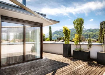 Geräumige Dachterrasse mit Holzboden, großen Schiebetüren und weitem Bergblick.