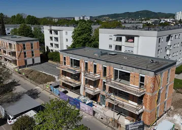 Luftaufnahme von Neubauten in Rohbauweise mit umliegenden Wohngebäuden und grüner Umgebung.