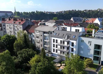 Luftaufnahme einer Wohnsiedlung mit verschiedenen Gebäudetypen und viel Grünfläche in städtischer Umgebung.