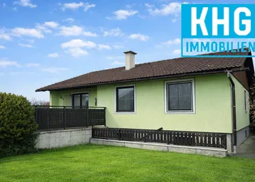 Seitenansicht des Hauses mit grünem Anstrich, braunem Dach und einem kleinen Rasenbereich.