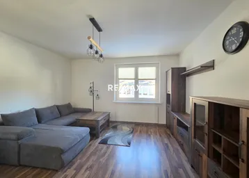 Geräumiges Wohnzimmer mit bequemer Couch, Holzboden und modernen Möbeln, ideal zum Entspannen.