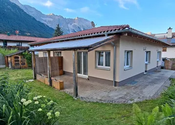 Einfamilienhaus mit großem, gepflegtem Garten, überdachter Terrasse und beeindruckendem Bergblick.