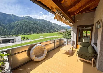Geräumiger Balkon mit Sitzgelegenheiten, Holzbalkendecke und atemberaubendem Bergblick.